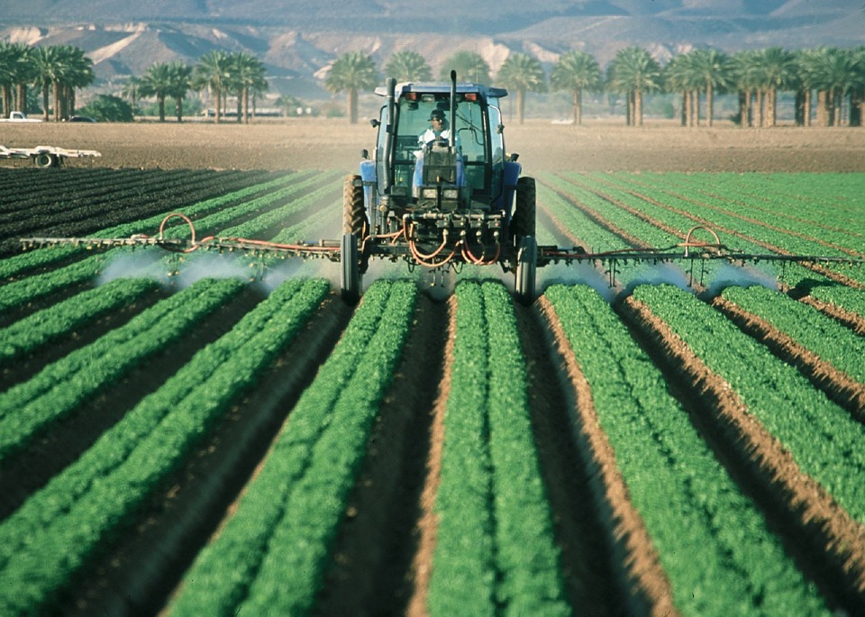 Un tracteur agricole répandant des pesticides dans un champ